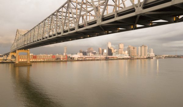 The sun breaks through storm clouds to light the New Orleans Skyline reflecting in the Mississippi River