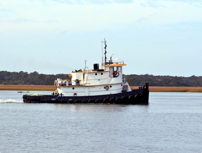 tugboat pulling a barge on a body of water using vessel management software from BargeOps